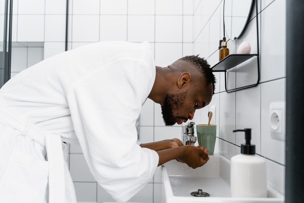 man washing his beard on the sink